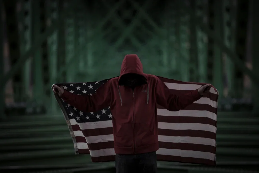 An undocumented immigrant holding an American flag, pondering the question "can undocumented immigrants file a personal injury claim?"