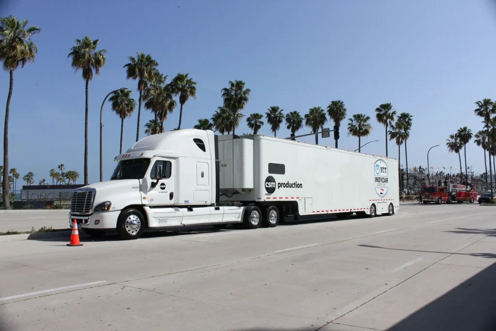 A truck parked at Long Beach on a sunny day, with blue skies and palm trees.